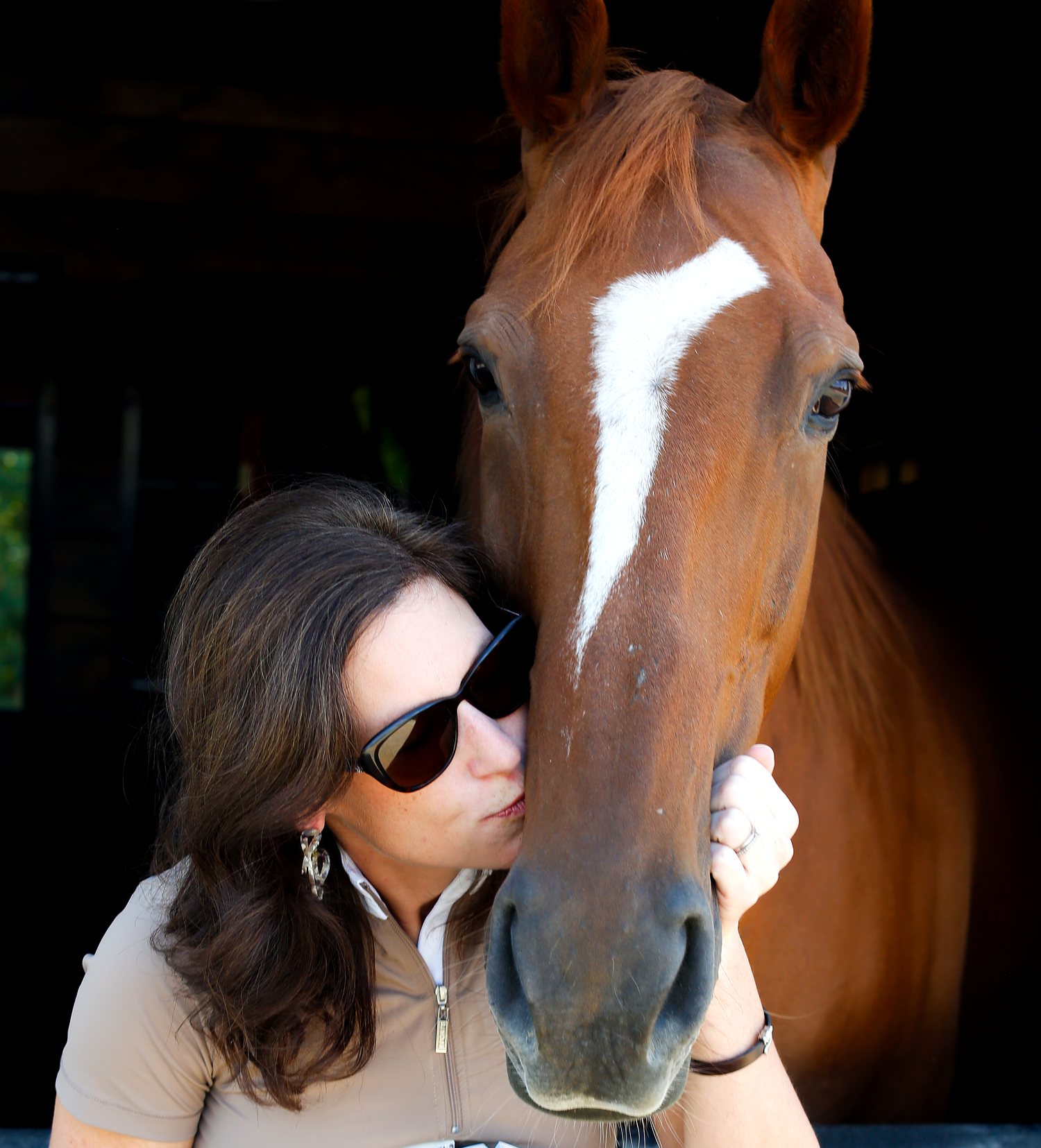 Author Laurie Berglie kissing the nose of her chestnut horse in a Maryland barn